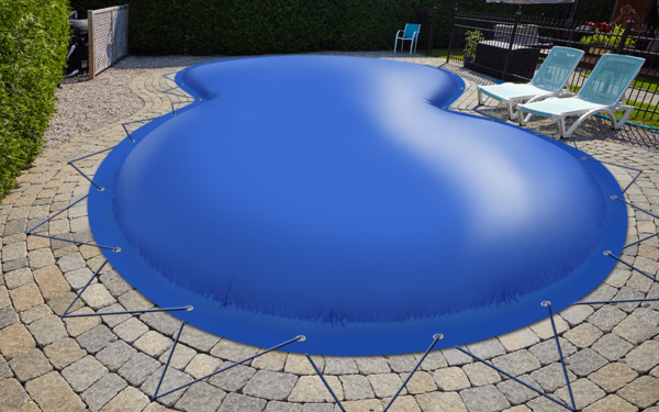 Auf einer Steinterrasse steht ein nierenförmiger Pool, der mit einer blauen, aufblasbaren Poolabdeckung abgedeckt und mit Seilen befestigt ist. Auf der rechten Seite stehen neben einer Hecke zwei weiße Liegestühle mit blauen Kissen.