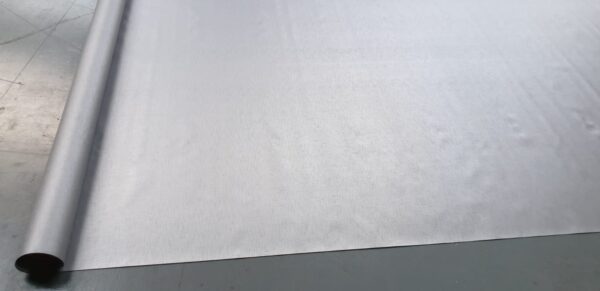 Eine große Rolle hellgrauer Stoff ähnlich dem LKW PVC Planen Reste, teilweise abgerollt mit einer weichen Textur, die subtil Licht einfängt und anmutig geschwungene Kanten hat.