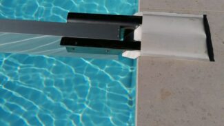 Der Schneeträger für Stangenabdeckungen bedeckt teilweise einen Pool mit klarem, blauem Wasser. Eine Metallleiter steht auf dem hellen Poolrand, während das Sonnenlicht Reflexionen und Wellen auf der Oberfläche erzeugt.