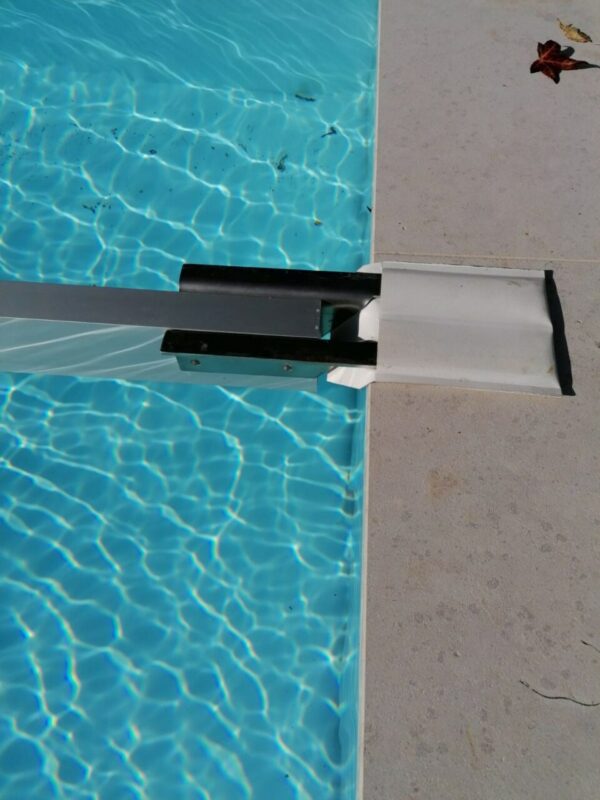 Der Schneeträger für Stangenabdeckungen bedeckt teilweise einen Pool mit klarem, blauem Wasser. Eine Metallleiter steht auf dem hellen Poolrand, während das Sonnenlicht Reflexionen und Wellen auf der Oberfläche erzeugt.